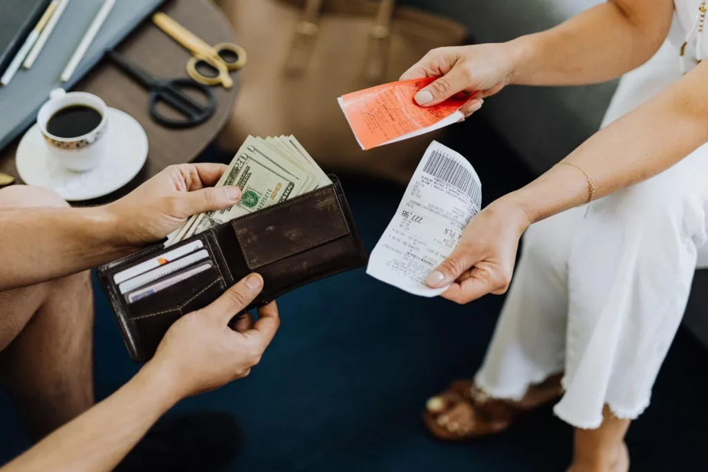 Close-up of hands exchanging US dollar bills, symbolizing a financial transaction or payment.