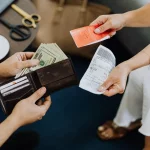 Close-up of hands exchanging US dollar bills, symbolizing a financial transaction or payment.